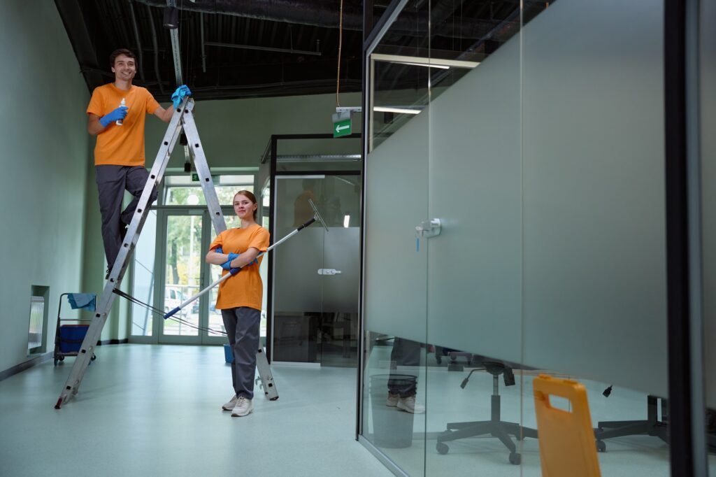 Certified janitors holding tools near ladder and looking at camera